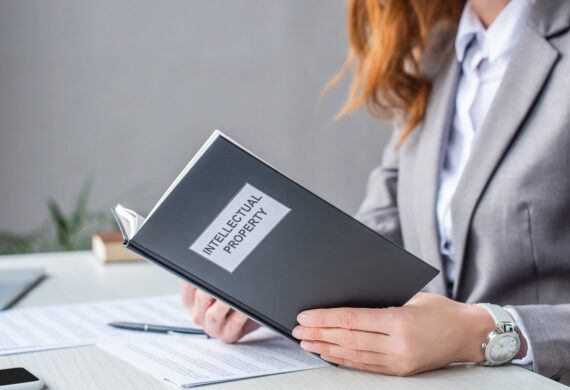 female lawyer holding book with intellectual property lettering at workplace on blurred